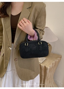 Detail view of a vintage rectangular black leather bag with gold handles and embossed logo