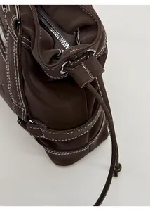 Detailed close-up of dark brown leather tote bag with white contrast stitching and drawstring