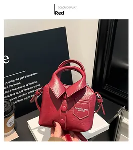 Détail d'un sac à main rouge en forme de chemise avec boutons et col sur un bureau
