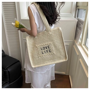 Détail d'un grand cabas de plage beige avec broderie Love Life et patch à franges