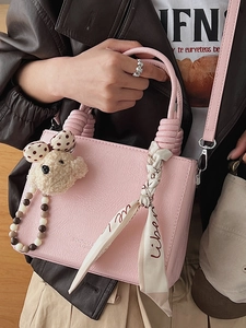 Pink crossbody bag with textured leather, knotted handle and plush bear charm