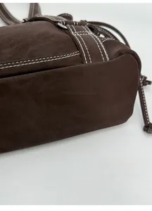 Detail view of the wide bottom structure and white contrast stitching on the brown tote bag