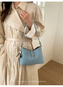Detail of light blue pebble leather bag with silver twist lock and furry charm accessory