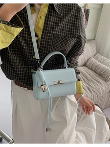 Detailansicht der hellblauen Ledertasche mit silbernem Herzanhänger und Metalldrehverschluss