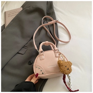 Détail du sac à main rose avec rivets argentés et pendentif ours en peluche marron