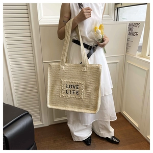 Détail d'un cabas tissé beige avec broderie LOVE LIFE noire et grande bandoulière tressée