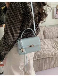 Detail der hellblauen Leder-Tasche mit silbernem Herzanhänger und Lederquasten-Verzierung
