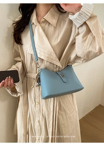 Detailed macro view of the silver metal clasp on a light blue pebbled leather bucket bag