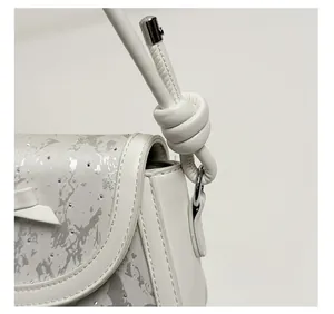 Détail de la bandoulière à nœud et du tissu strass sur le sac à main blanc chic