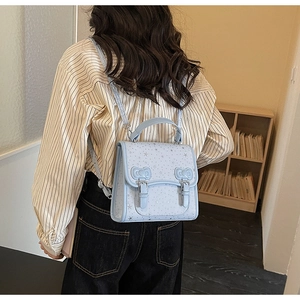Detail of light blue backpack featuring silver star patterns and decorative 3D bow accents