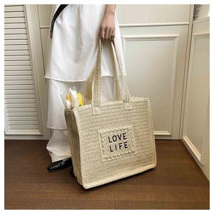Vue détaillée du sac cabas en paille tressée avec texte LOVE LIFE et tulipes