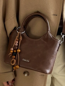 Brown leather bucket bag with wooden bead tassel charm and leather label for women