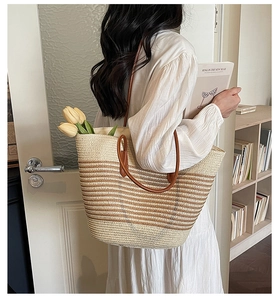 Detail of striped woven straw tote bag with brown leather straps and tulip decor