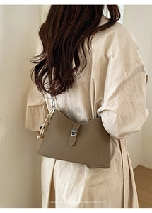 Close-up of brown textured leather bag with silver twist lock and decorative side chain