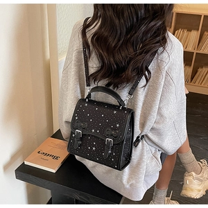 Star pattern black backpack with twin buckles shown on a model in a cozy setting