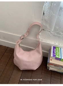 Detail of adjustable strap with silver metal eyelets on pink leather crescent bag