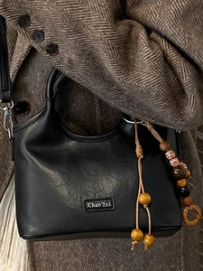 Elegant black leather bucket bag with retro colorful beads shown on herringbone coat
