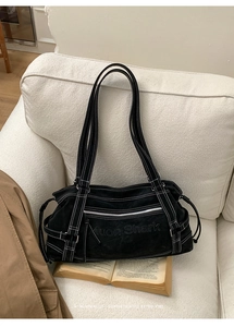 Detail view of black canvas tote bag featuring contrast stitching and adjustable buckles