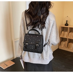 Detail of black bow backpack with silver star patterns and adjustable shoulder strap