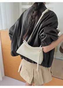 Chic cream white leather shoulder bag detail on model with brown jacket and skirt