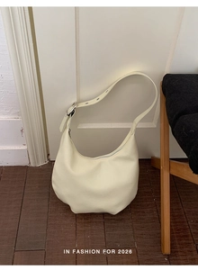 Detail of cream semi-circle hobo bag featuring smooth faux leather and silver metal buckle