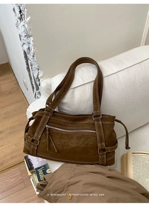 Detailed view of dark brown faux leather tote with Muon Shark embossed logo and white stitching
