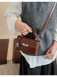 Nahaufnahme der dunkelbraunen Lacklederhandtasche mit Silberverschluss und Bärenanhänger