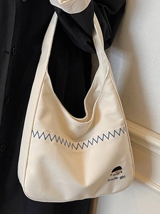 Minimalist beige canvas shoulder bag with blue stitching and Docile Girl embroidery