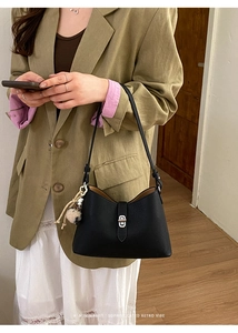 Detail of black lychee grain leather hobo bag with silver turn-lock and fur ball charm