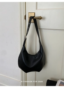 Detail of black faux leather hobo bag with adjustable strap and silver metal eyelets
