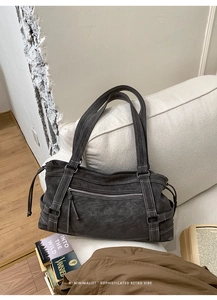 Detail of dark grey distressed faux leather tote bag with white contrast stitching accents