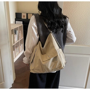 Detail view of khaki canvas tote bag with metal snap button pocket and wide strap