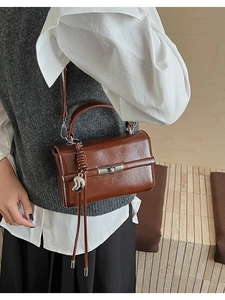Detailansicht einer braunen Vintage-Lederhandtasche mit Mondanhänger und Drehverschluss