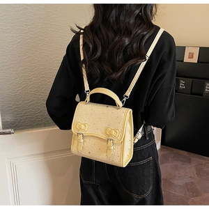 Detail of light yellow backpack with bow decorations and tiny star patterns
