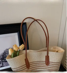 Close-up of durable leather handles and woven texture on a striped beach straw tote bag