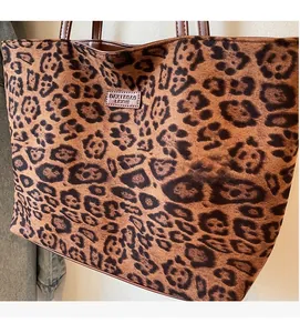 Détail du tissu imprimé léopard avec bordure en cuir et logo de marque sur le sac