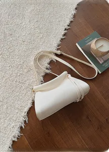 Vue de dessus d'un sac bandoulière crème avec fermeture magnétique sur tapis moelleux