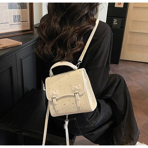 Detail of cream-colored handbag with silver star print and twin bow buckles decor