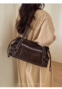 Detail of deep brown tote with contrast stitching and Moon Shark embossed logo