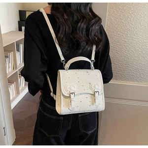 Detail showing bow accents and star prints on a minimalist creamy white backpack