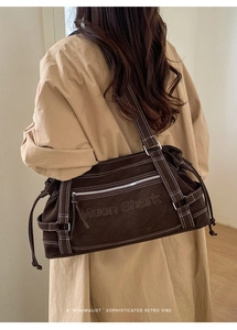 Close-up of brown suede shoulder tote bag featuring detailed white contrast stitching