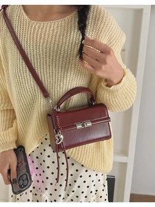 Detaillierte Nahaufnahme der dunkelroten Vintage-Lederhandtasche mit Herzanhänger aus Silber