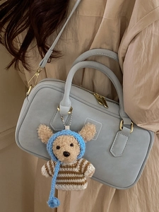 Minimalist light blue handbag with golden hardware and cute bear charm for daily commute