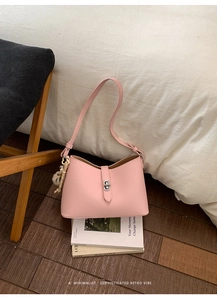 Detail view of pink lychee pattern bucket bag with silver clasp and plush ball accessory