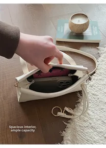 Intérieur spacieux du sac à bandoulière en cuir blanc montrant le téléphone et le portefeuille