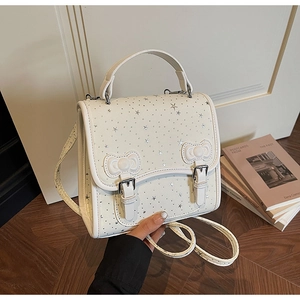 Detail of white PU leather bag with silver stars and decorative bow accents in a home setting