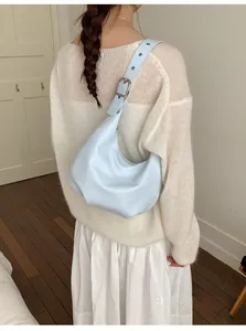 Detail of light blue leather hobo bag with adjustable silver buckle in a cozy home setting