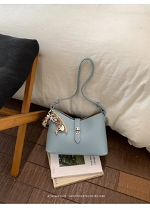 Detail of light blue pebble leather bag featuring silver lock and heart charm pendant