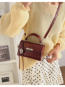 Detail der burgunderroten glänzenden Ledertasche mit Herzanhänger und Quaste am Model