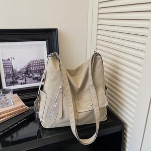 Detail view of khaki nylon tote bag featuring diagonal zipper and magnetic flap pocket